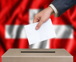 Hand fügt Brief in Urne, Flagge im Hintergrund