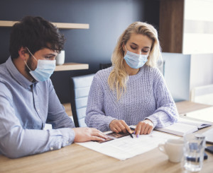 Frau und Mann arbeiten am Tisch mit Gesichtsmasken